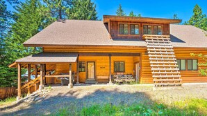 Eine Holzhütte mit überdachter Veranda, einer Treppe und einem Willkommensschild.