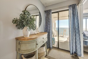 Una habitación con un tocador de madera, una planta en maceta, un espejo y vistas al balcón.