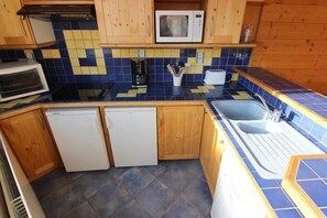 A compact kitchen with wooden cabinets, a microwave, a toaster, and a dishwasher.