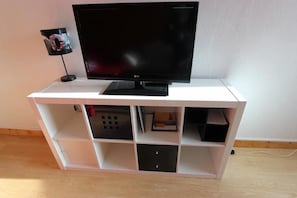 A flat-screen TV on a white entertainment unit with multiple storage compartments.