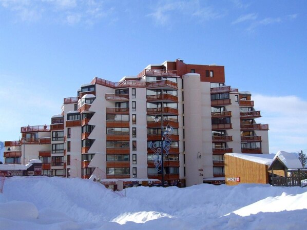 A multi-story hotel with balconies and a ski resort in the background.