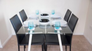 Un tavolo da pranzo con sei sedie, un piatto nero al centro e sei bicchieri blu.