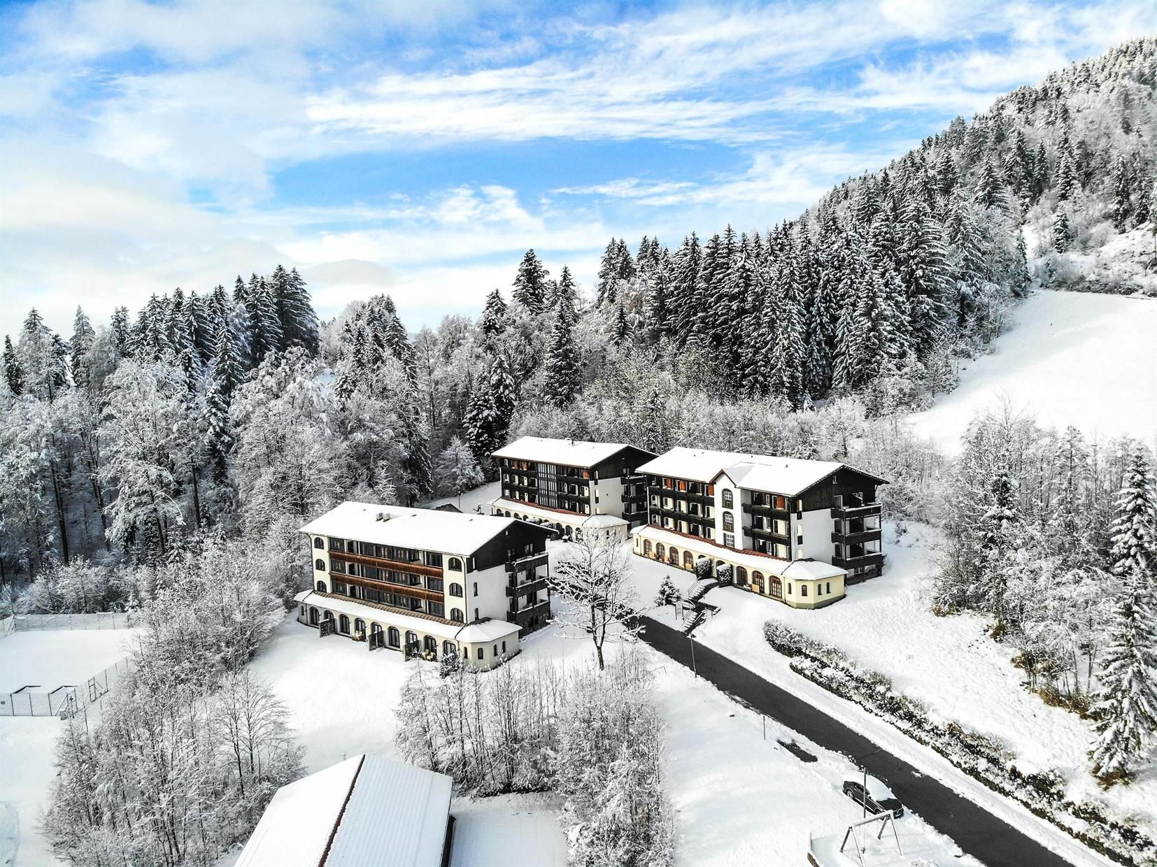 Een besneeuwde lodge met meerdere gebouwen, omgeven door een bebost gebied.