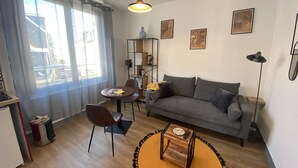 En moderne stue med en grå sofa, et rundt sofabord og en reol.