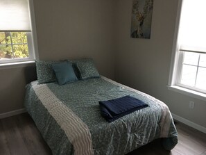 A bedroom with a bed, two pillows, a blanket, and a painting on the wall. - Fully remodeled house with amazing views. (Fairfield)