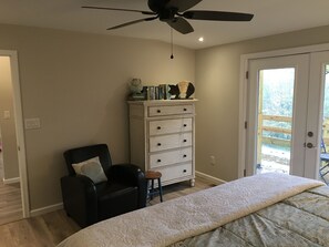 A bedroom with a bed, a chair, a dresser, and a ceiling fan.
