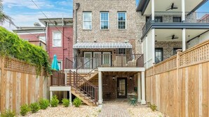 A two-story house with a brick facade, a covered patio, and a wooden fence. - Waldburg Garden by Tybee Vacation Rentals (Savannah)