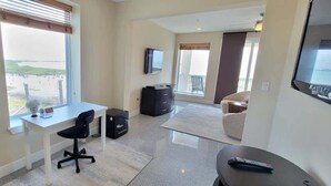 A hotel room with a desk, chair, television, and a view of a body of water. - Tortuga Bay 3 Bedroom Home by RedAwning (South Padre Island)