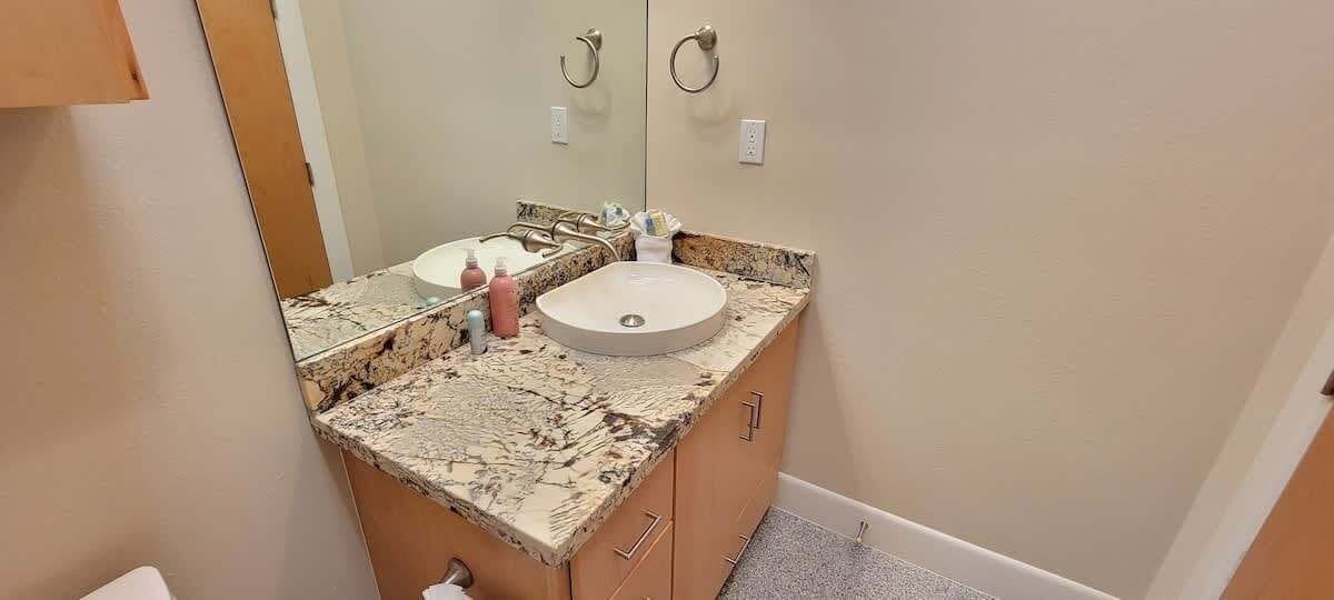 A bathroom with a marble countertop, a sink, and a mirror.