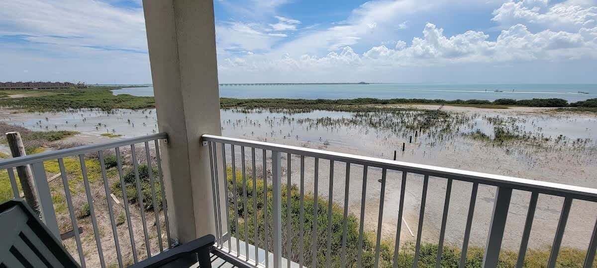 A balcony with a view of a beach and marshland.