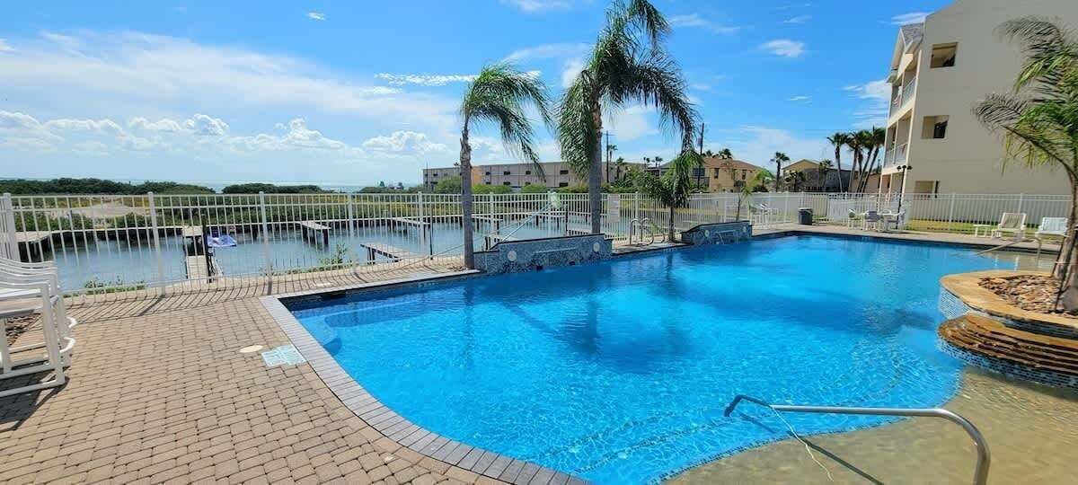 A swimming pool with a clear view of the surrounding area, including a building and palm trees.
