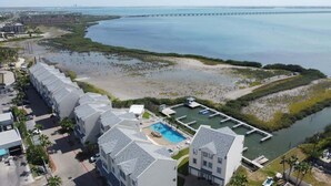 A resort with a pool, beachfront, and a pier in the background. - Tortuga Bay 3 Bedroom Home by RedAwning (South Padre Island)