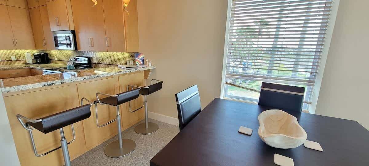 A modern kitchen with wooden cabinets, a built-in microwave, and a bar area with stools.