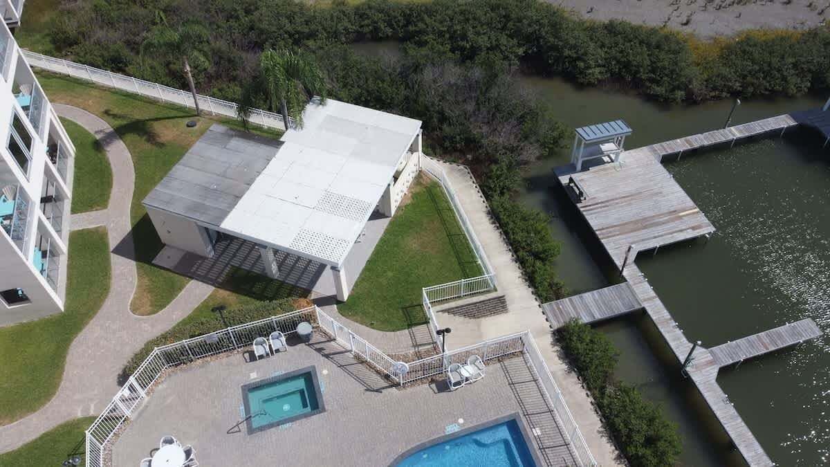 Vue aérienne d’un hôtel doté d’une piscine, d’un espace extérieur couvert et d’une jetée s’avançant dans une étendue d’eau.