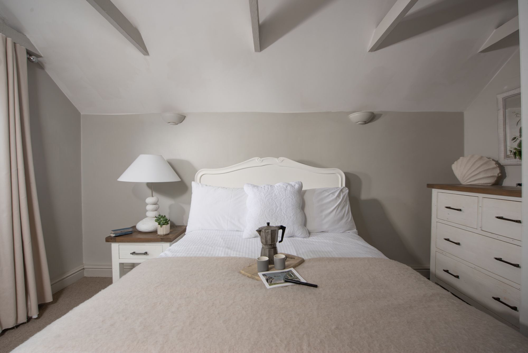 Una camera da letto con un letto, comodino, lampada e cassettiera.