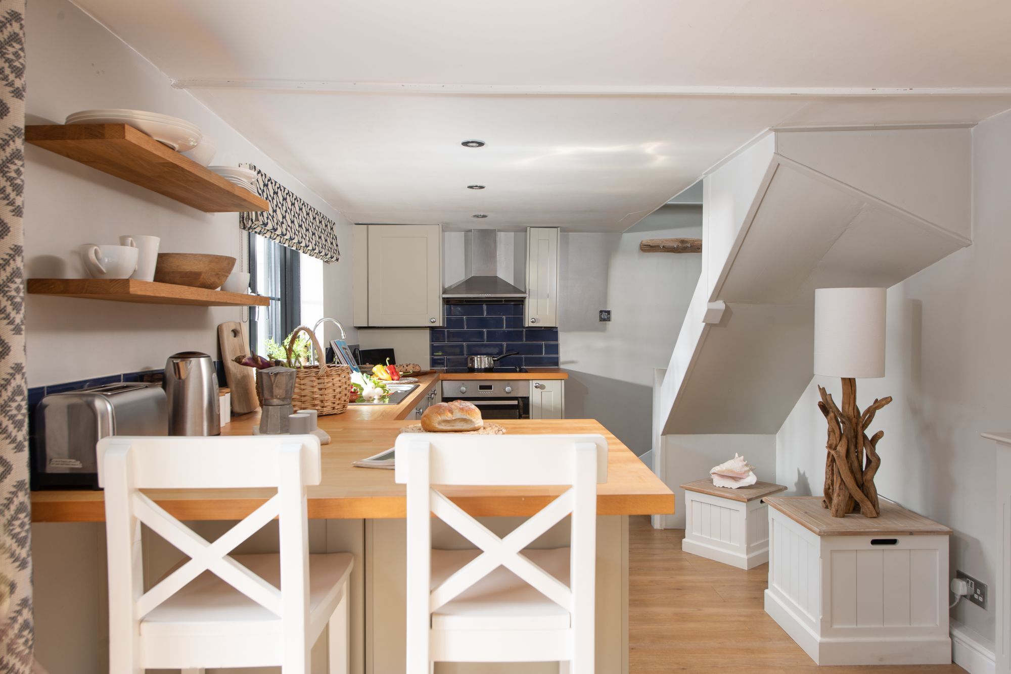 A modern kitchen with white cabinetry, a wooden island, and a dining area with white chairs.