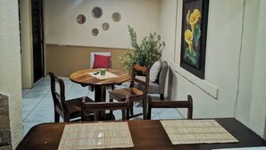 A dining area with a round table, chairs, a potted plant, and a wall-mounted fan. - Casa Central Playa Jacó Downtown A Pocos Pasos de la Playa (Jacó)