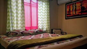 A bed with a patterned bedspread, a chair, and a painting on the wall. - Casa Central Playa Jacó Downtown A Pocos Pasos de la Playa (Jacó)
