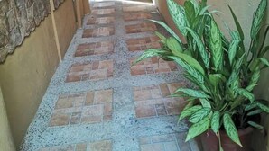 A narrow hallway with a tiled floor leading to a door with a metal gate. - Casa Central Playa Jacó Downtown A Pocos Pasos de la Playa (Jacó)
