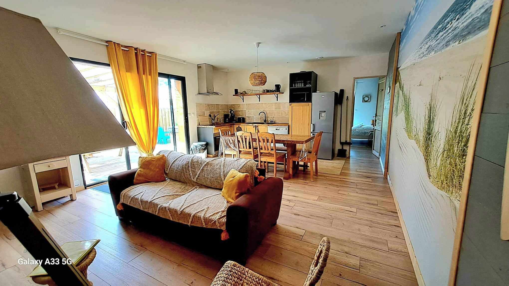 Un ambiente compatto con divano, tavolo da pranzo e angolo cottura.