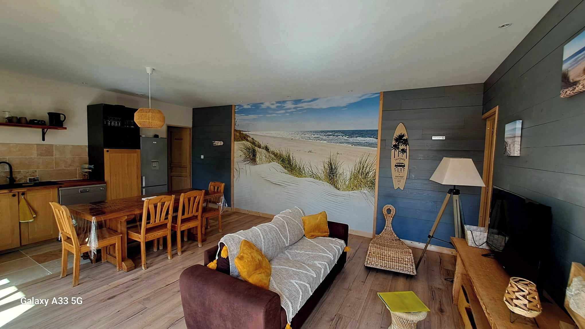 Een moderne woonkamer met een strandmuur, houten meubels en een surfboard decoratie.