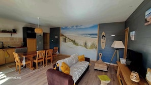 A modern living room with a beach mural, wooden furniture, and a surfboard decoration. - Les Bord'Océanes Villa Marensine and Villa Oyat – Private Sauna & Spa (Vielle-Saint-Girons)