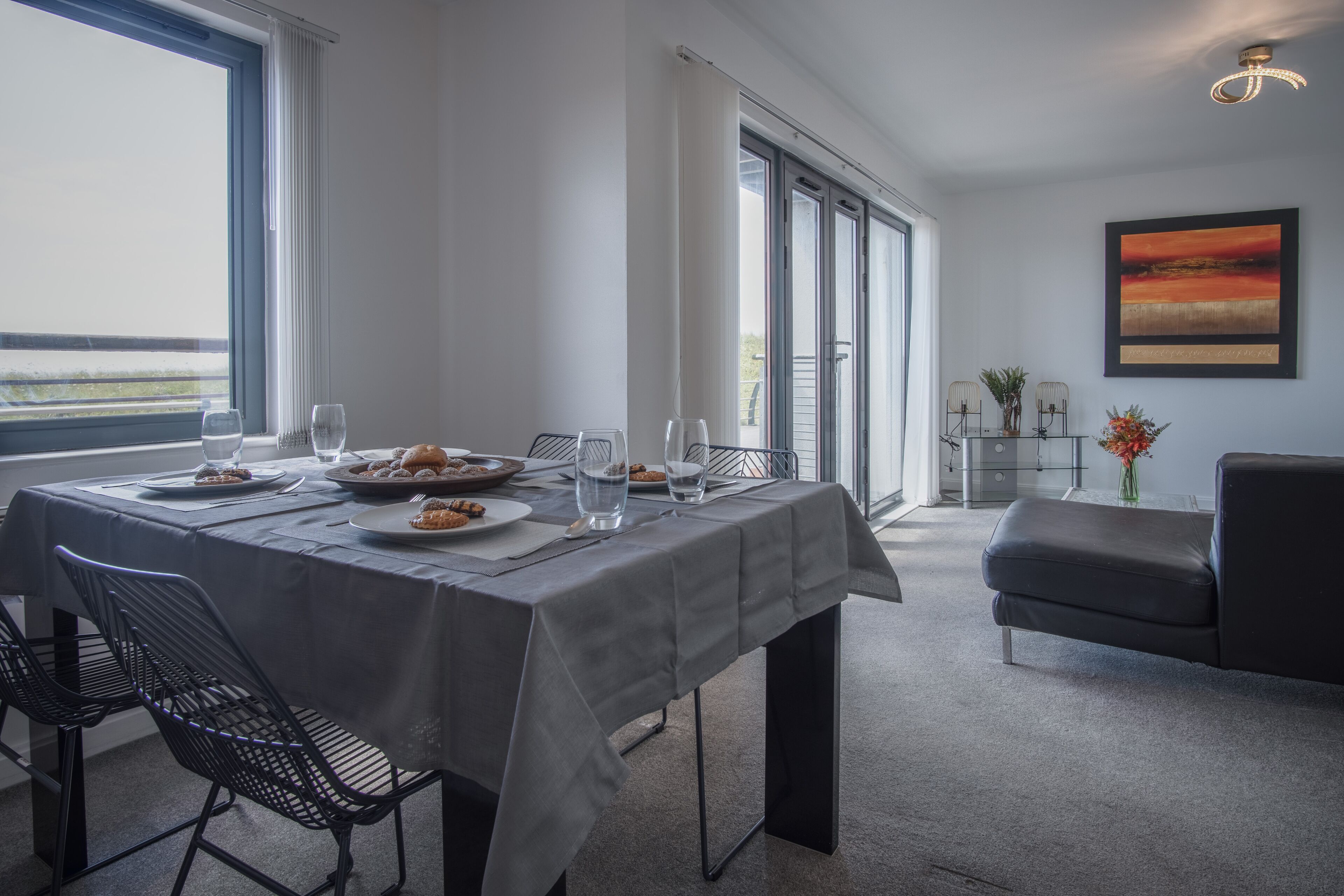 Un coin repas avec une table dressée pour deux personnes, un banc et une vue sur l’extérieur.