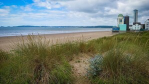 Une plage avec un sentier menant à des bâtiments, dont un phare et une haute tour.