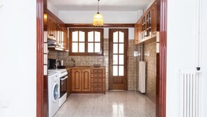 A compact kitchen with wooden cabinets, a washing machine, and a radiator. - Fabulous Apartment in Pireaus (Piraeus)