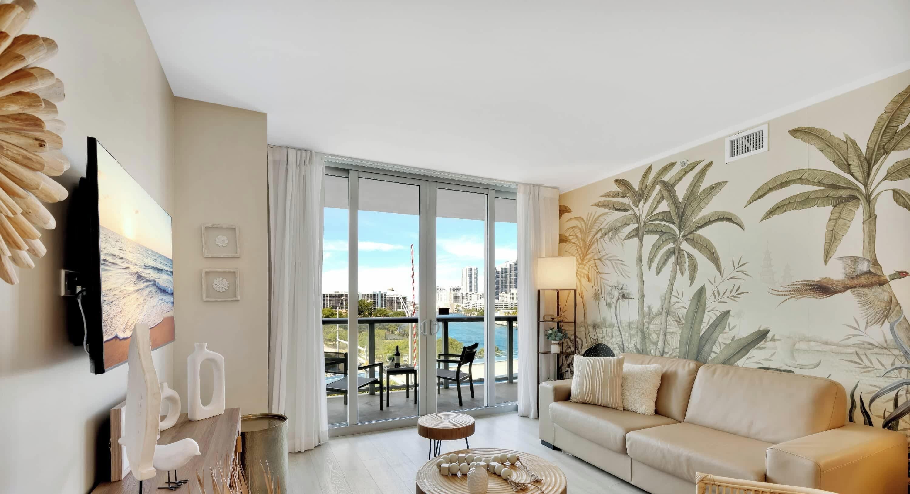 A modern living room with a sofa, a television, and a balcony with a city view.