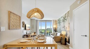 A dining area with a table set for four, a large woven pendant light, and a view of the outdoors through a sliding glass door.