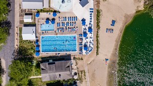 An aerial view of a resort with a swimming pool, beach area, and various amenities.