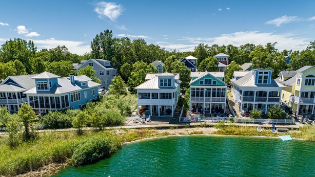 A coastal residential area with houses along the water, featuring large windows and balconies.