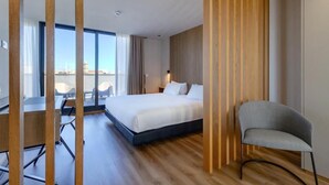 A modern hotel room with a large bed, a desk, and a chair. There is a view of the city through large windows. - Select Porto (Porto)