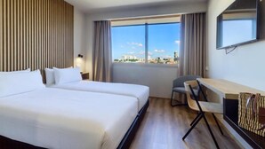 A hotel room with two beds, a desk, a chair, a TV, and a large window with a city view. - Select Porto (Porto)