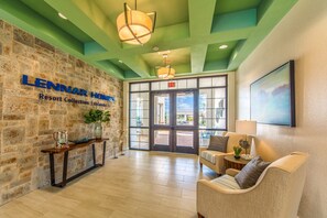 Experience the warm welcome of Lennar Homes Resort Collection's inviting lobby, featuring a stone wall, comfortable seating, and a beautiful view of the outdoor area.