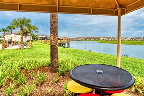 Relax in a serene lakeside setting with a tranquil outdoor seating area featuring a round table and three chairs.