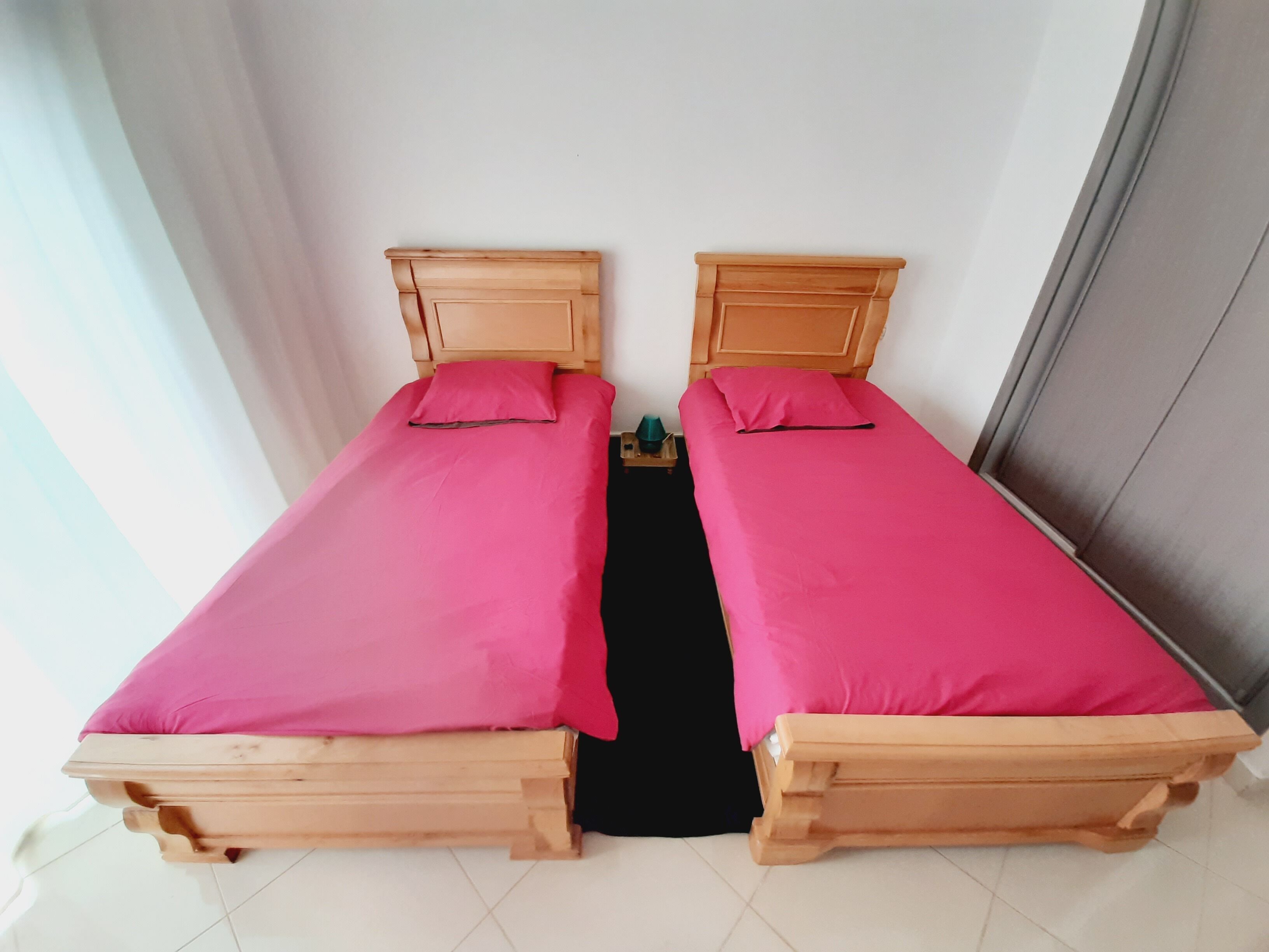 Une chambre avec un lit double, dotée de deux têtes de lit en bois et de couvre-lits roses assortis.