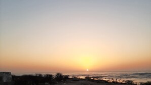 Een zonsondergang boven een strand met een heldere lucht.