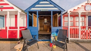 Une rangée de cabanes de plage aux couleurs vives, avec une pancarte indiquant « VENT » au centre.