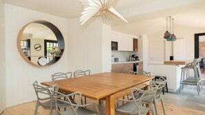 Un comedor moderno con una mesa de madera y sillas grises, un espejo redondo y una lámpara de techo original.