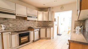 A modern kitchen with white cabinets, a built-in oven, and a tiled backsplash. - Maesbury Manor (Oswestry)