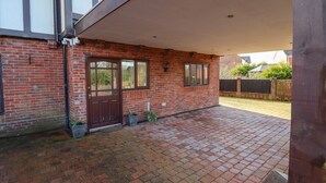 A brick building with a covered patio area, a door, and windows. - Maesbury Manor (Oswestry)