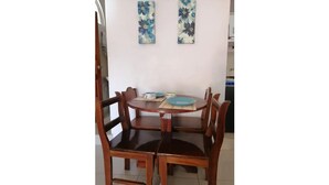 Un coin repas avec une table ronde en bois et quatre chaises. Deux décorations florales sont accrochées au mur au-dessus de la table.