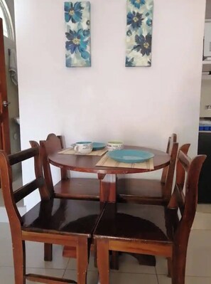 A dining area with a round wooden table and four chairs. There are two wall-mounted floral decorations above the table.