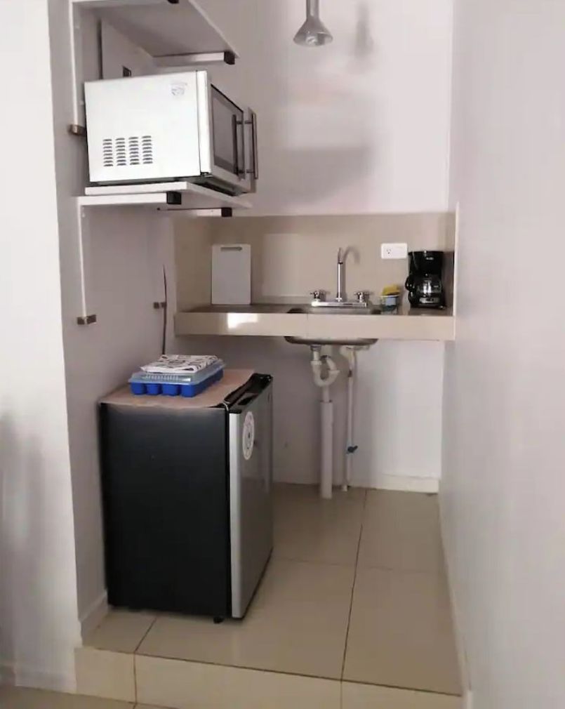 A compact kitchenette with a microwave, a small refrigerator, a sink, and a coffee maker.