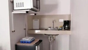 Une petite cuisine équipée d’un four à micro-ondes, d’un petit réfrigérateur, d’un évier et d’une machine à café.