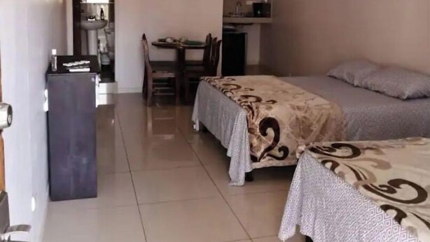Une chambre avec deux lits, un ventilateur de plafond et un coin repas comprenant une table et des chaises.
