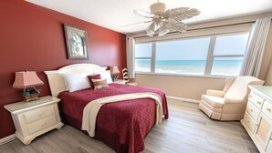 Une chambre avec un grand lit, une table de chevet, une chaise et une vue sur la plage.