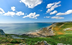 Un paysage côtier avec un ciel dégagé, une plage et un terrain rocheux.